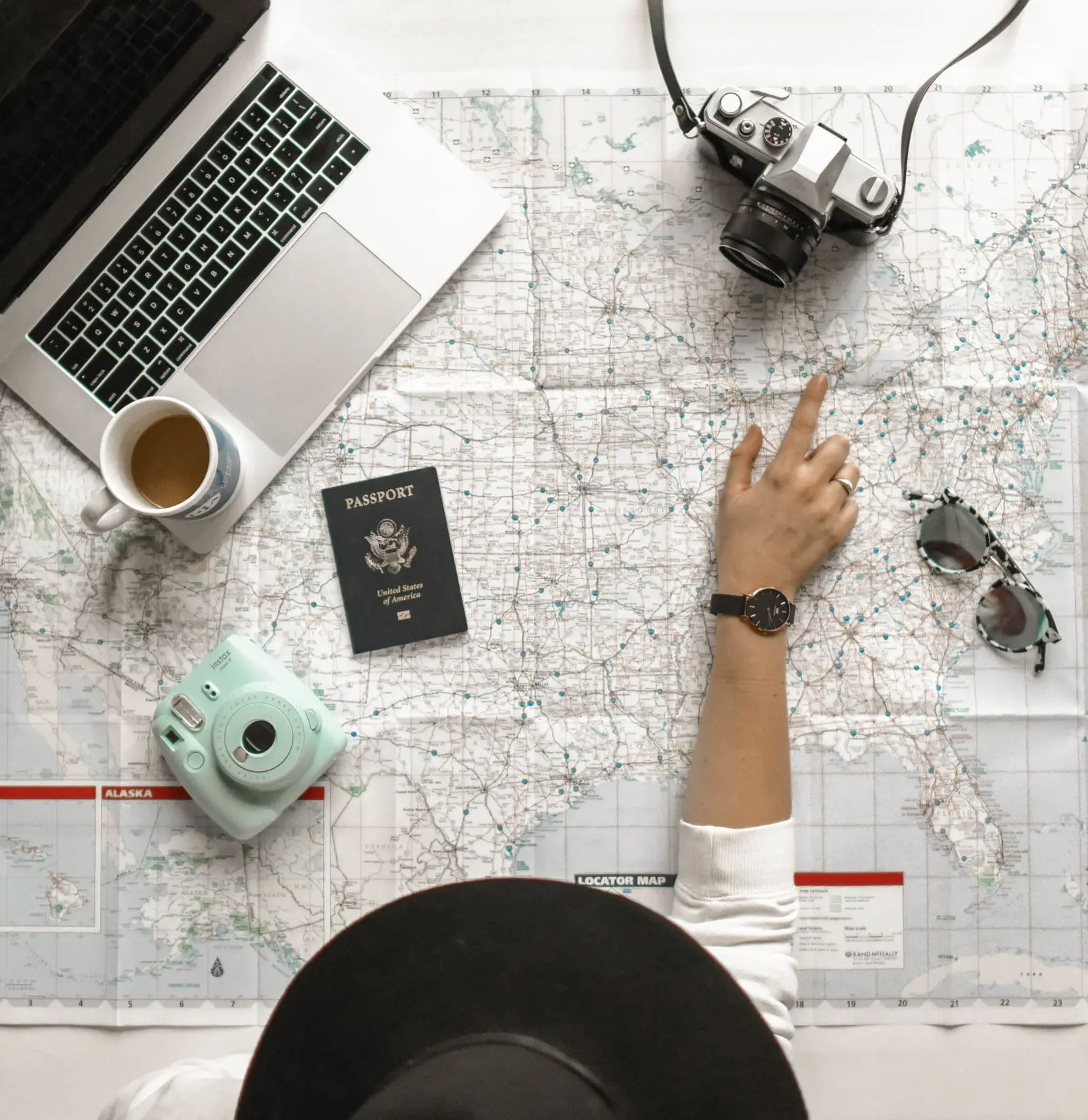 Pointing at a city on a map beside a passport and a laptop