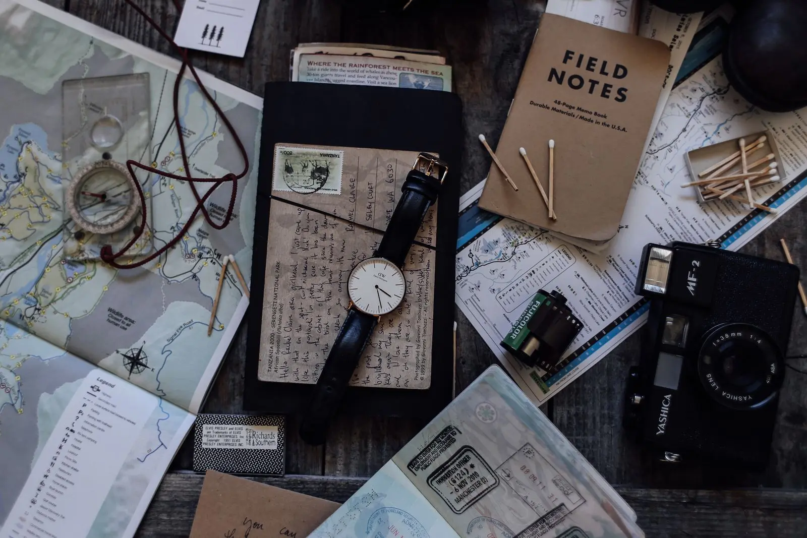 A field notebook, a watch and printed tickets laid out on a desk