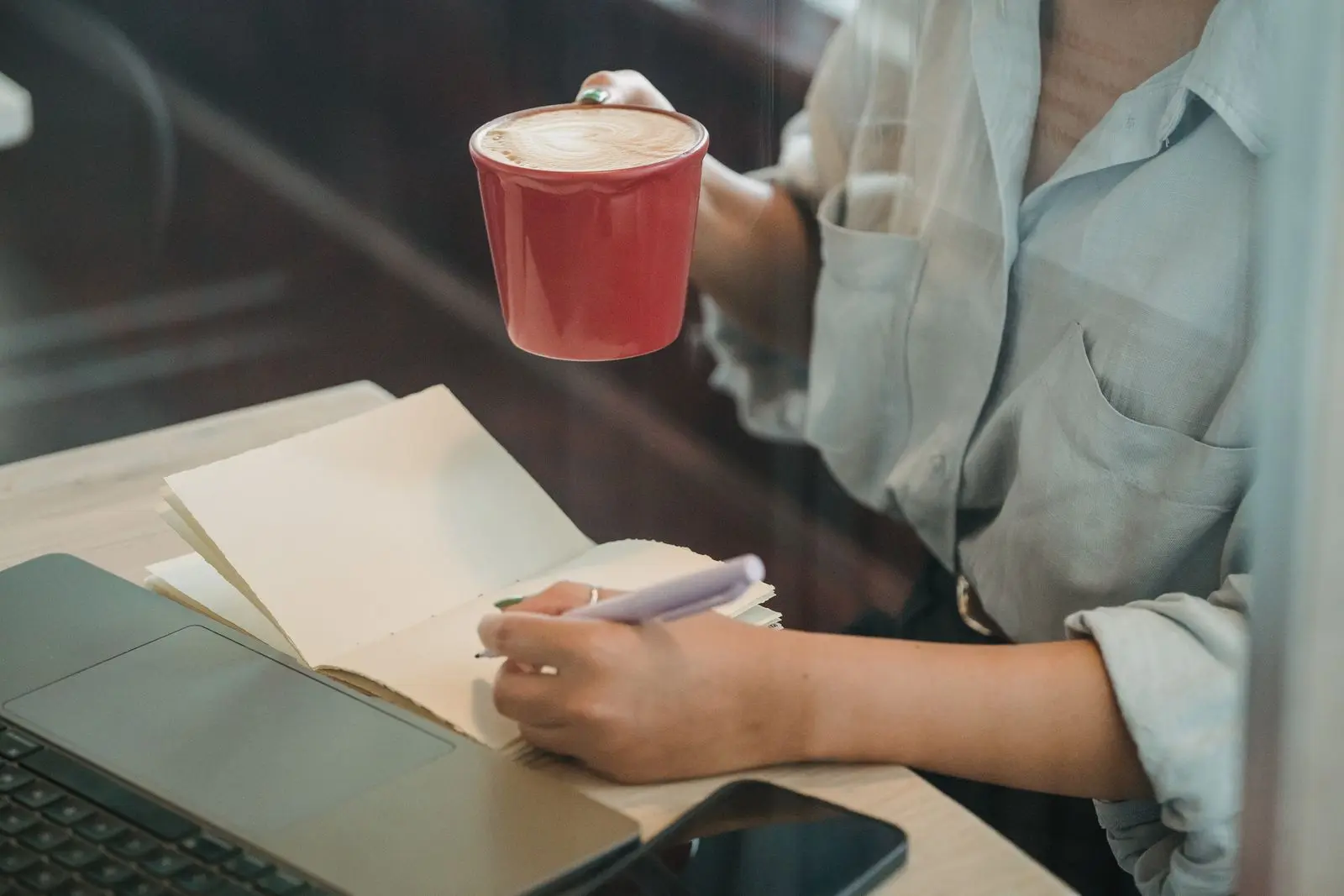 Writing a question in a notebook over a cup of coffee